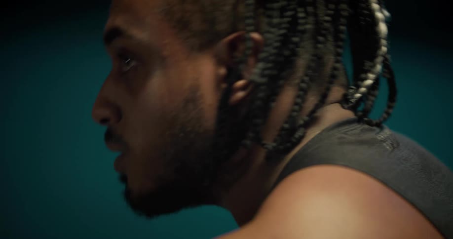 A young black man with sweat running down his face wipes his forehead