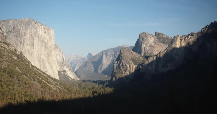 Shadow covers part of forest in valley while mist covers portion in background