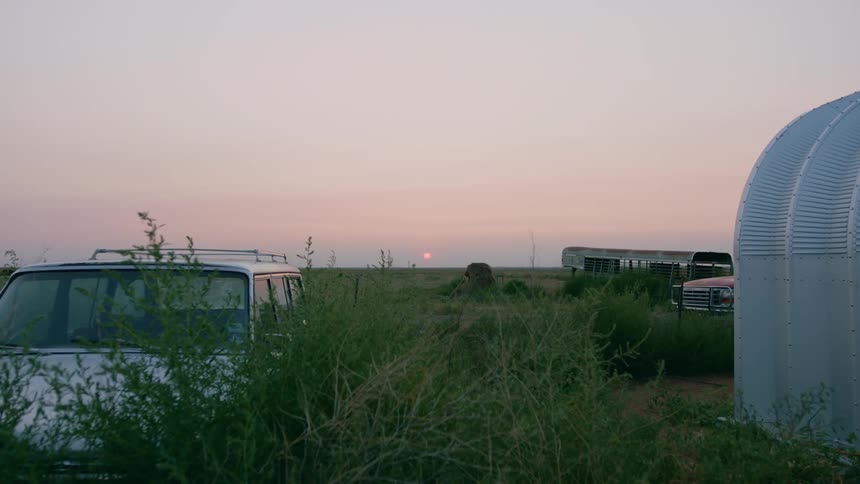 Abandoned vehicles in a Texas field at sunset