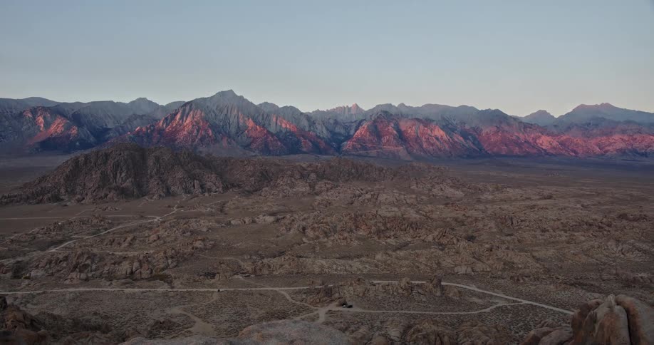 Landscape view of desert plains and hills next to a mountain range at evening