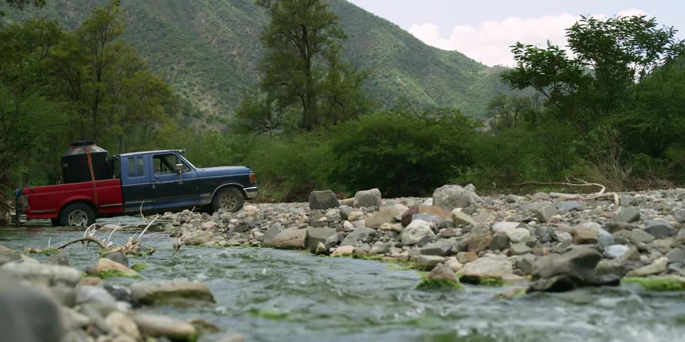 A pickup truck sits parked along a river