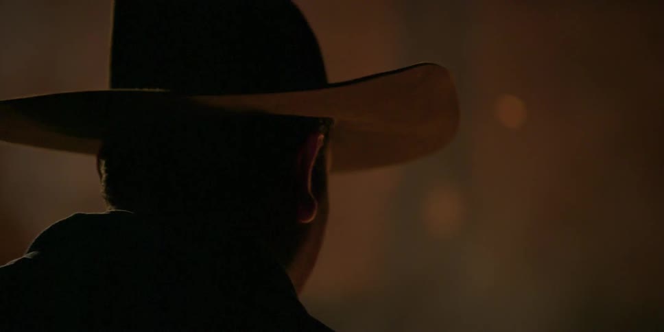 The back of a mans head wearing a hat near fire sparks
