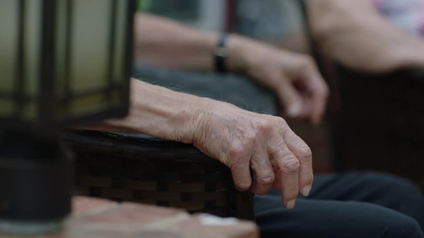 A close up shot of an elderly man's hand as he sits on a patio