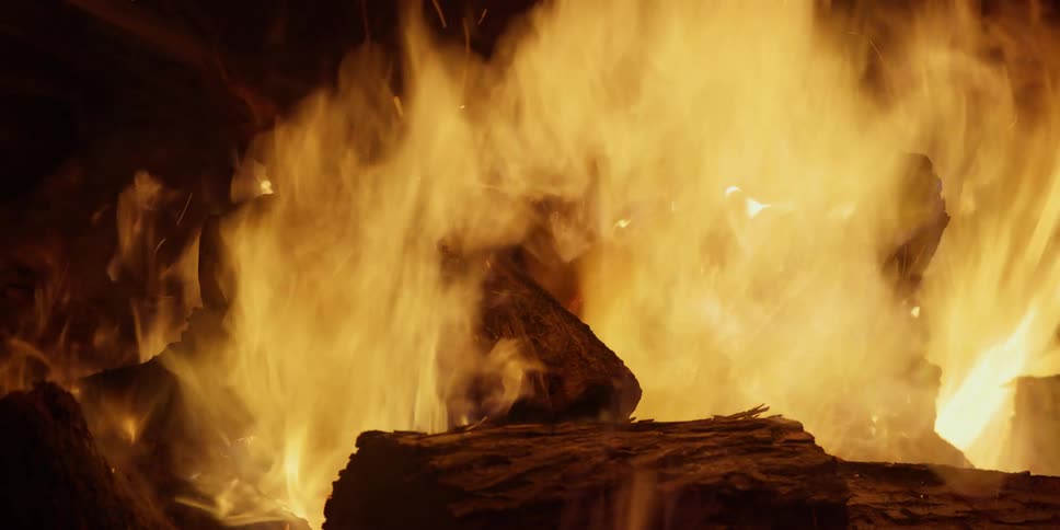 The flames of a bonfire burn brightly in the darkness