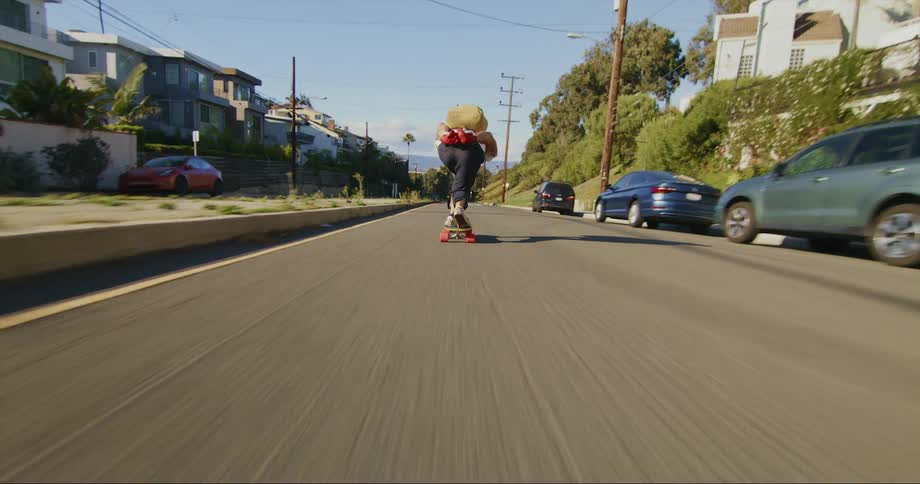 A skateboarder rides down a busy neighborhood street