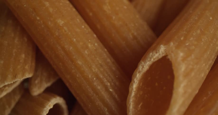 Ribbed penne pasta tubes sit in a pile
