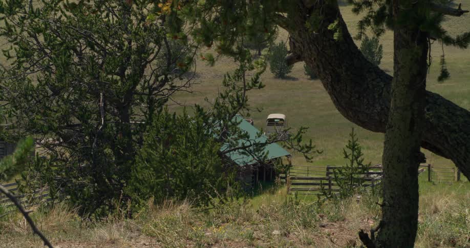 A small house sits at the bottom of a grassy hill
