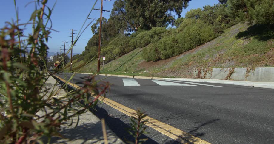 A person rides a skateboard on a rural road at daytime