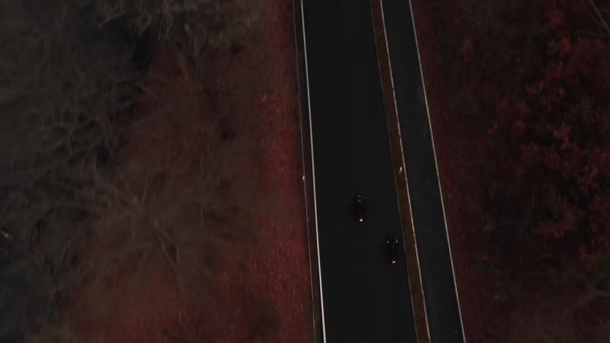 Aerial view of two motorcycles driving on a road through the countryside at fall