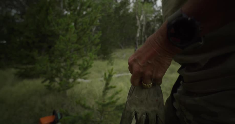 A man puts on work gloves after getting out of his vehicle
