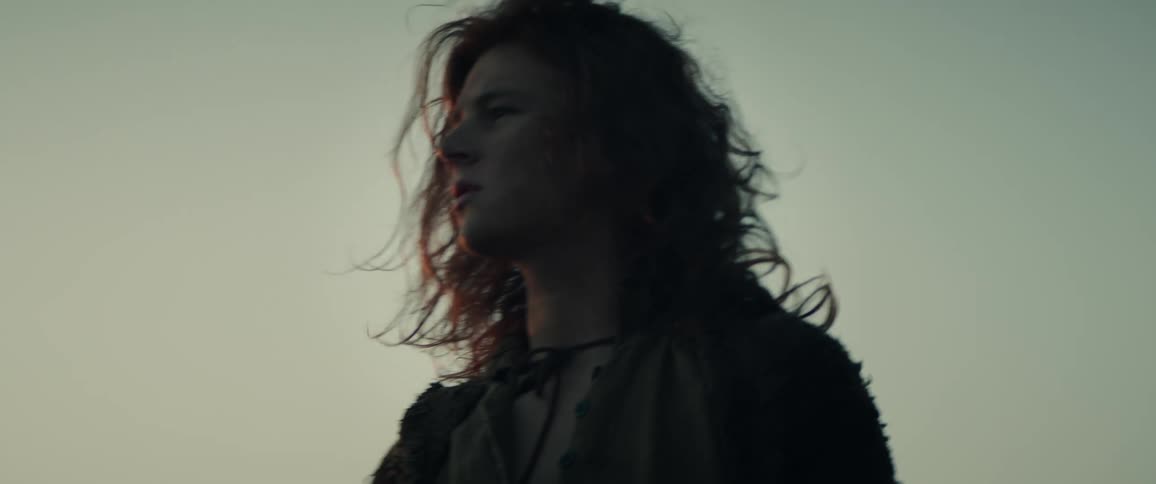 A young medieval man walks on a windy day