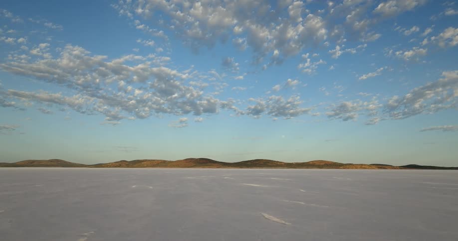 Aerial view of the white flat plains on the desert next to the mountains
