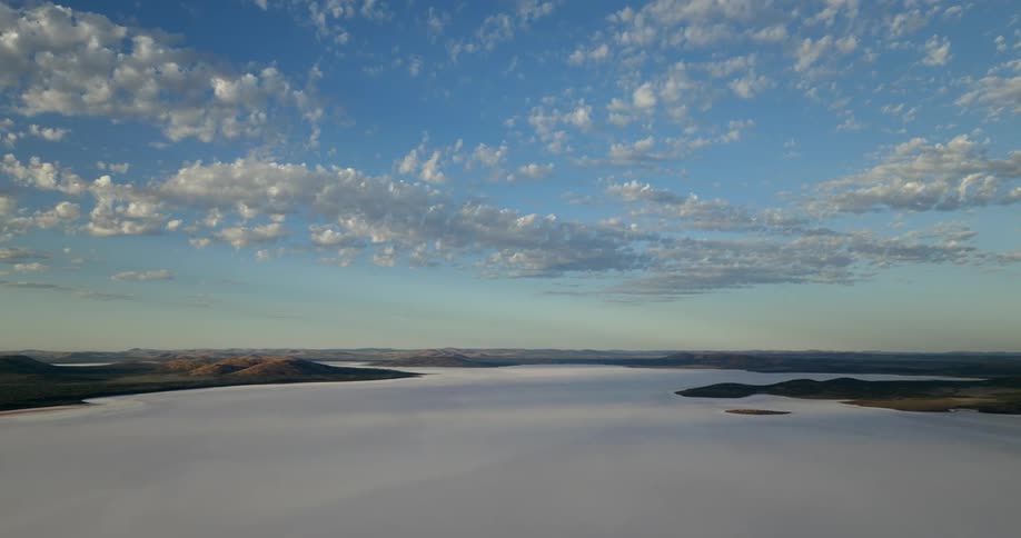 Clouds float over a frozen lake in a blue sky