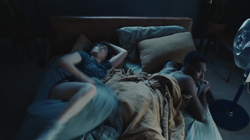 Time lapse of a man and woman cuddling and tossing and turning in bed and pushing a cat out of the way