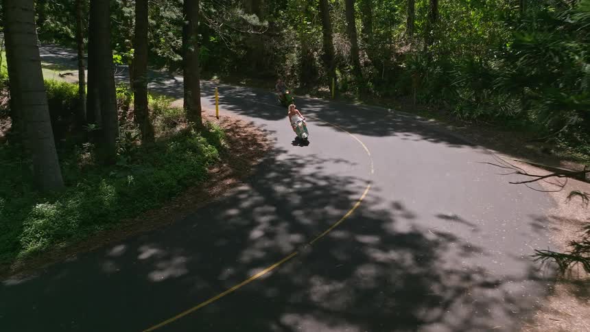 Man and woman riding scooters ride along highway through woods