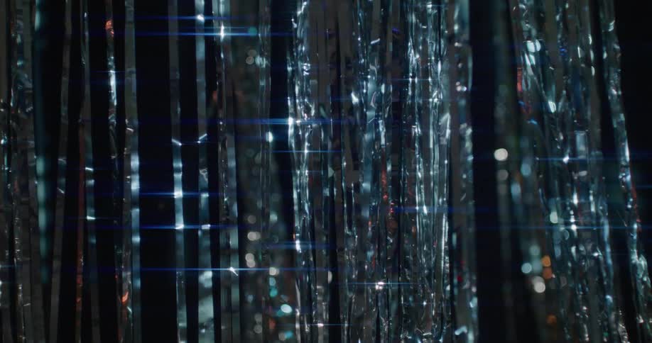 Silver tinsel strips shimmer and wave against dark background