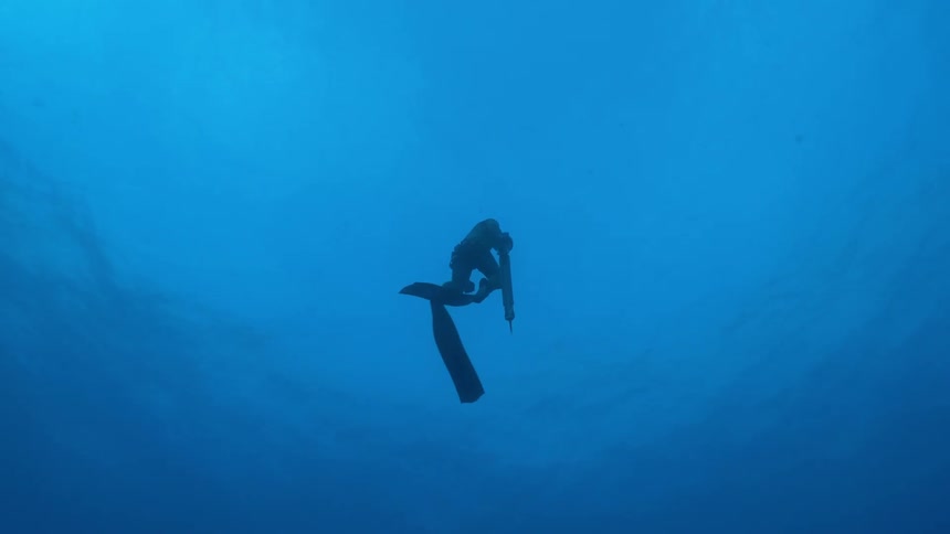 Diver swimming underwater in blue ocean waters