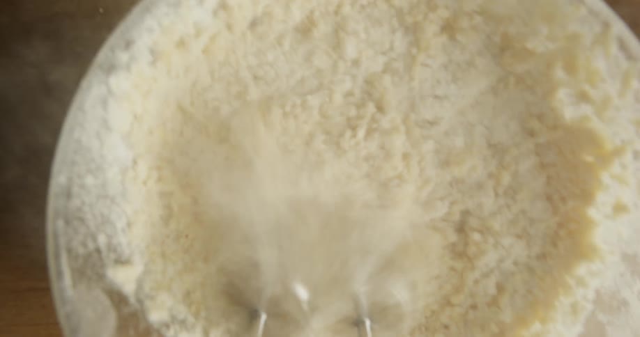 Point of view shot of a hand mixer mixing eggs and flour inside a bowl