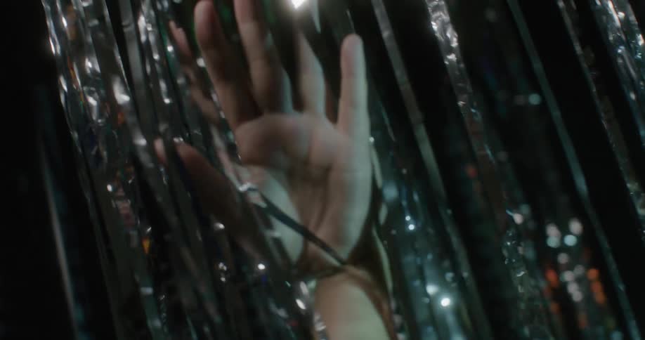 A woman runs her hand through streamers