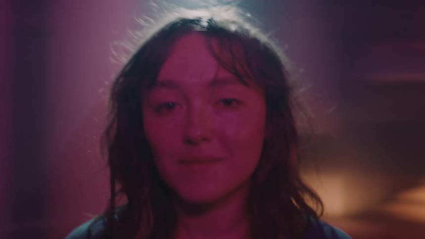 A womans facial expression changes and she sneezes as the buildings and lights behind her spin past