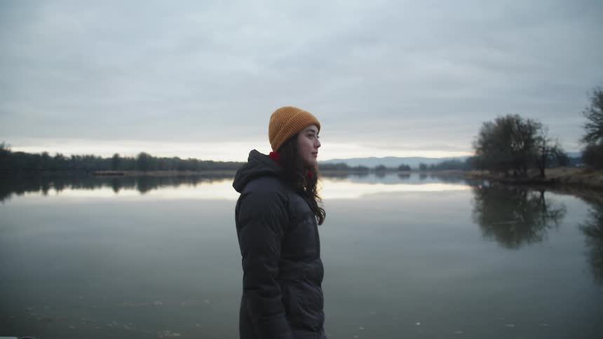 A young woman walks along the shore