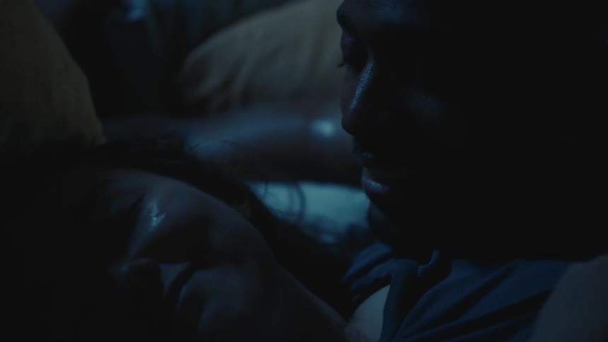 A woman smiles and makes a shushing sign with her finger as she tries to sleep