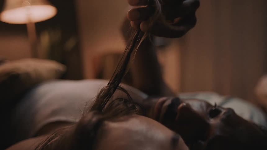 Man playing with womans hair while laying in bed relaxing