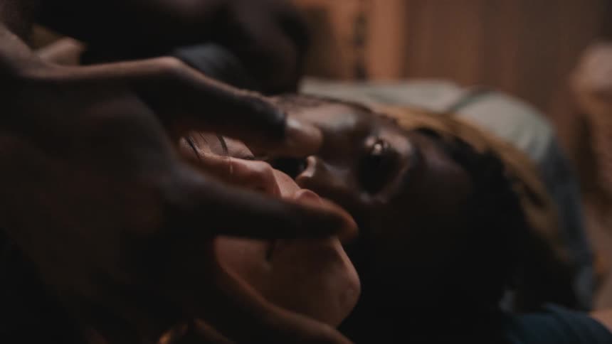 Black persons hand pinches the lips and mouth of a white person