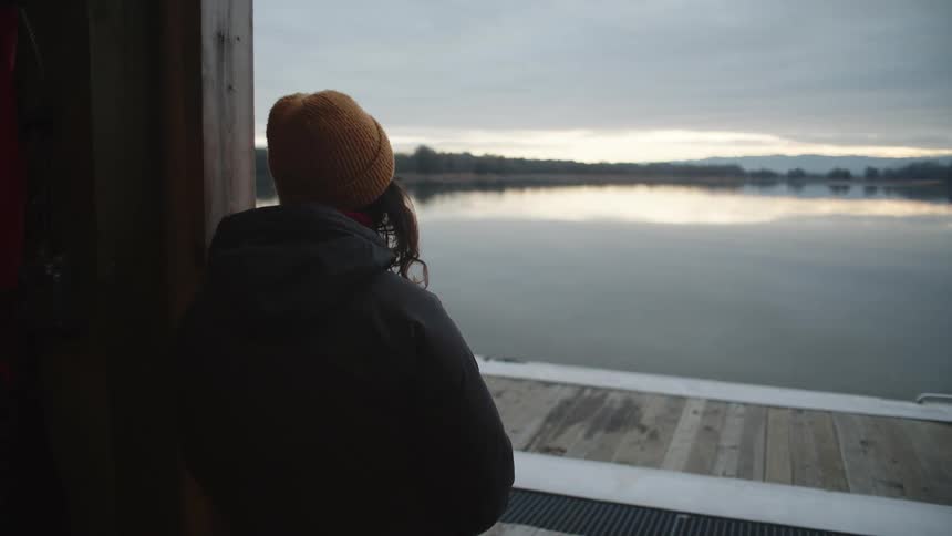 Young woman reclined on the entrance of a building in front of a lake at evening