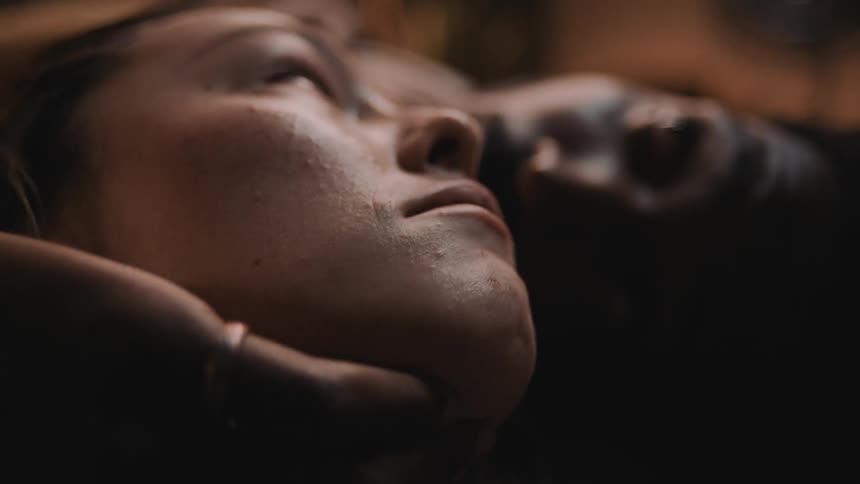 Man smiles while grasping womans face as her mouth opens and closes