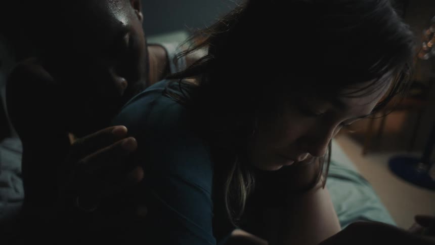 A woman is looking at the flame on a lighter and pulling away from a man who is caressing her arm