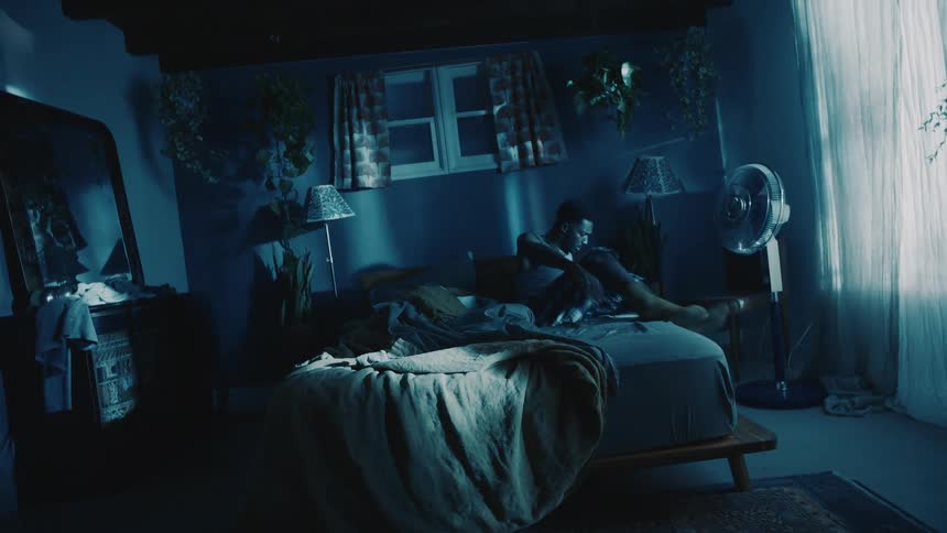 Surreal footage of an upside down room rotating while the man sleeping in the bed wakes up