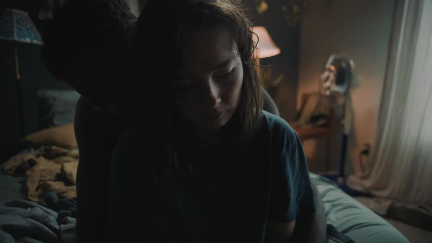 Young couple sitting on the bed hugging on a dimly lit bedroom