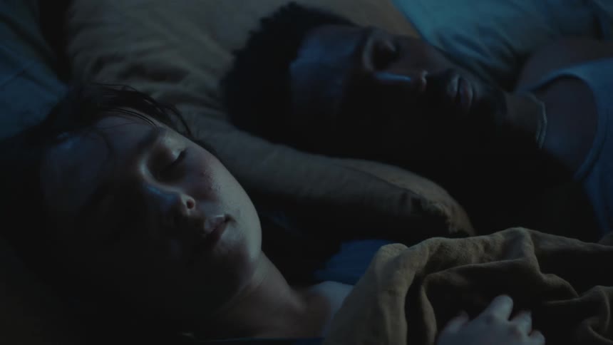 A man and woman are sleeping in bed