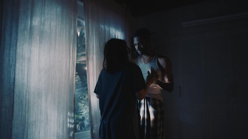 A couple is dancing in the dark in front of a window in a room