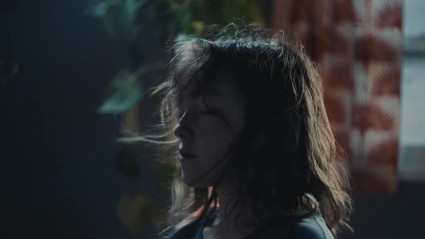 A bright light flashes as wind blows a womans hair as she stands still