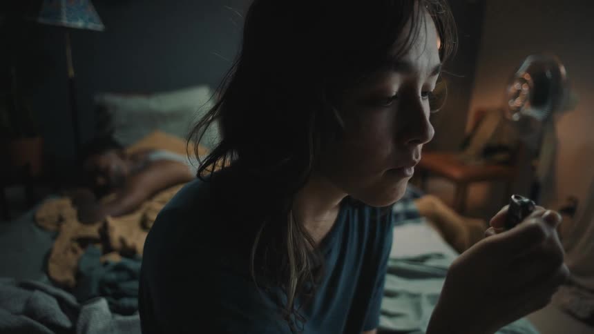 Woman flicking a lighter on and off in bedroom darkness
