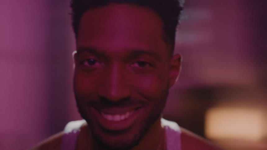 A man stares directly into the camera as the room around him seems to spin