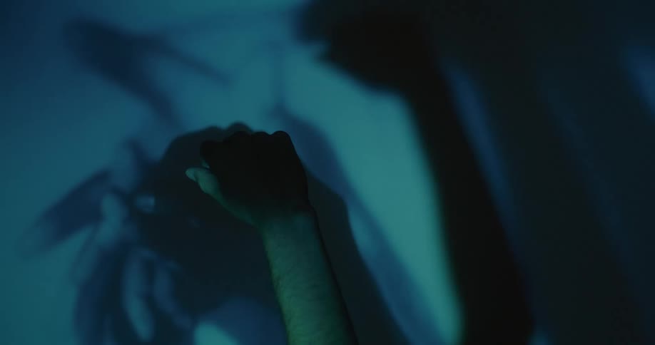 A hand moving in darkness creating many hand shadows