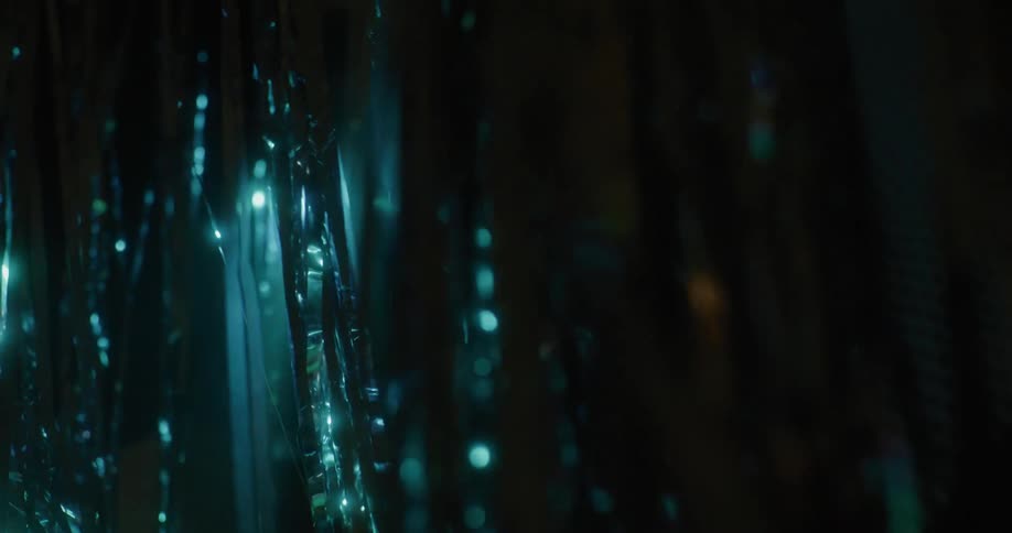 Blue tinted light shines onto fluttering silver ribbons and casts pattern