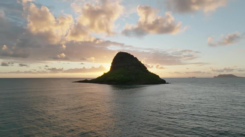 Aerial of a rock in middle of ocean at sunrise