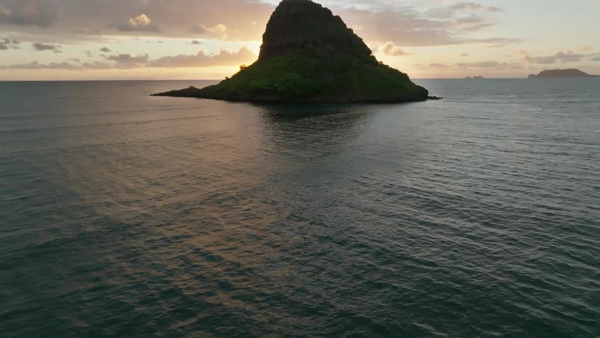 Aerial view of the silhouette of a solitary island in the ocean at evening