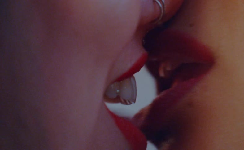 Close up of the red lips of two women kissing and talking