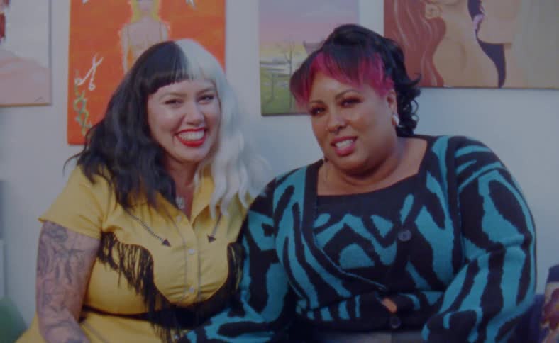 Two women laugh while posing in their living room