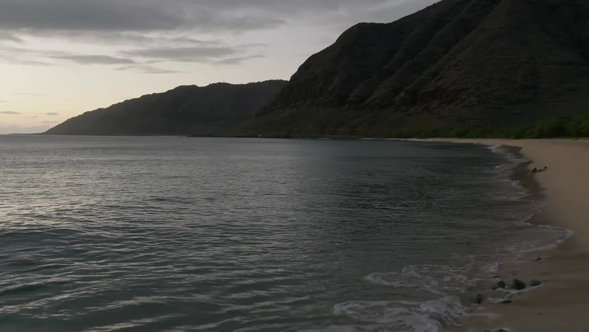 Aerial of ocean gently lapping on the shoreline at sunrise