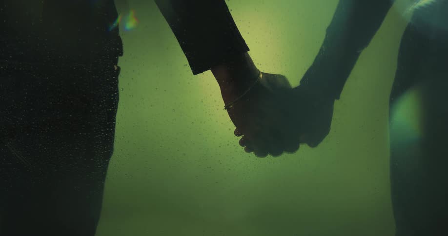 A couple holding hands in greenish lighting
