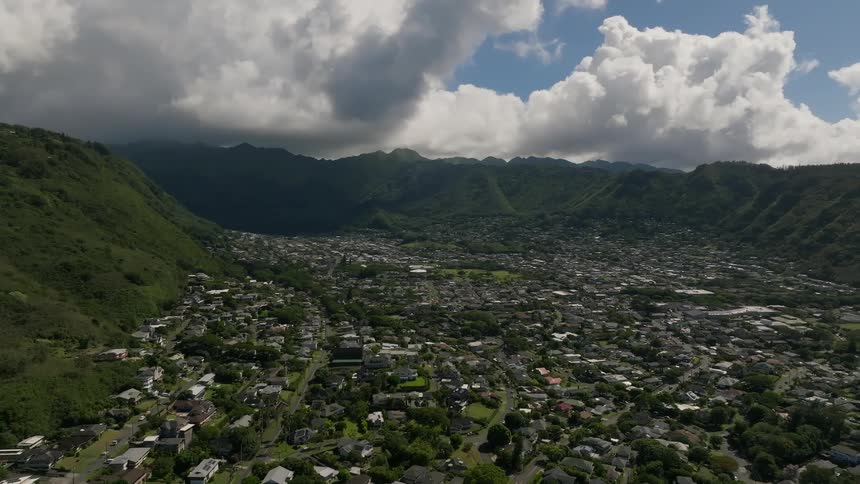 Town fills misty valley between mountains under a cloudy sky