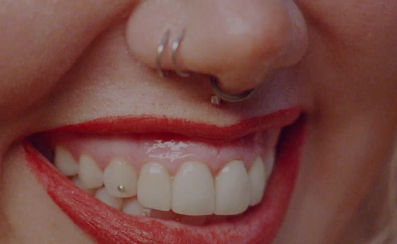 Close up of the mouth of a woman wearing nose rings smiling