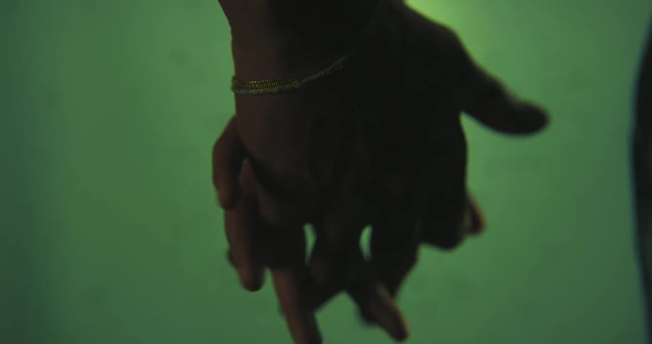 Couple holds hands against a pale green background