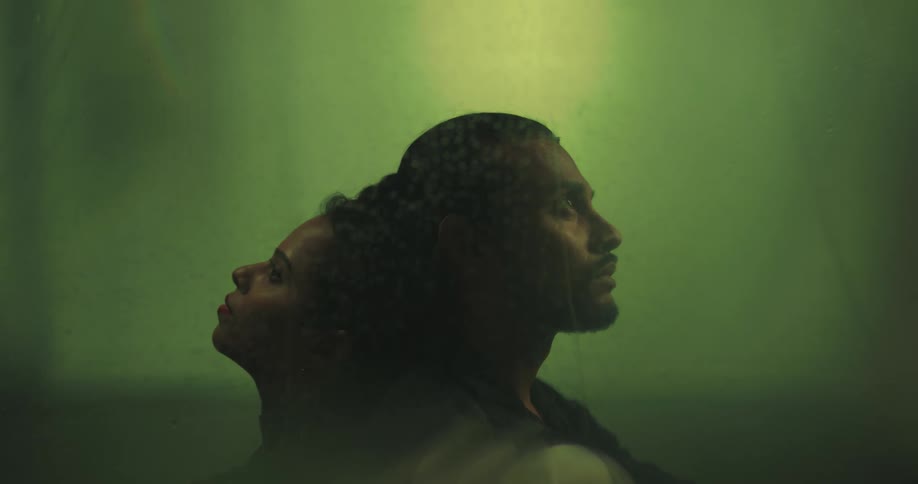Man and woman sit back to back behind the window while raining
